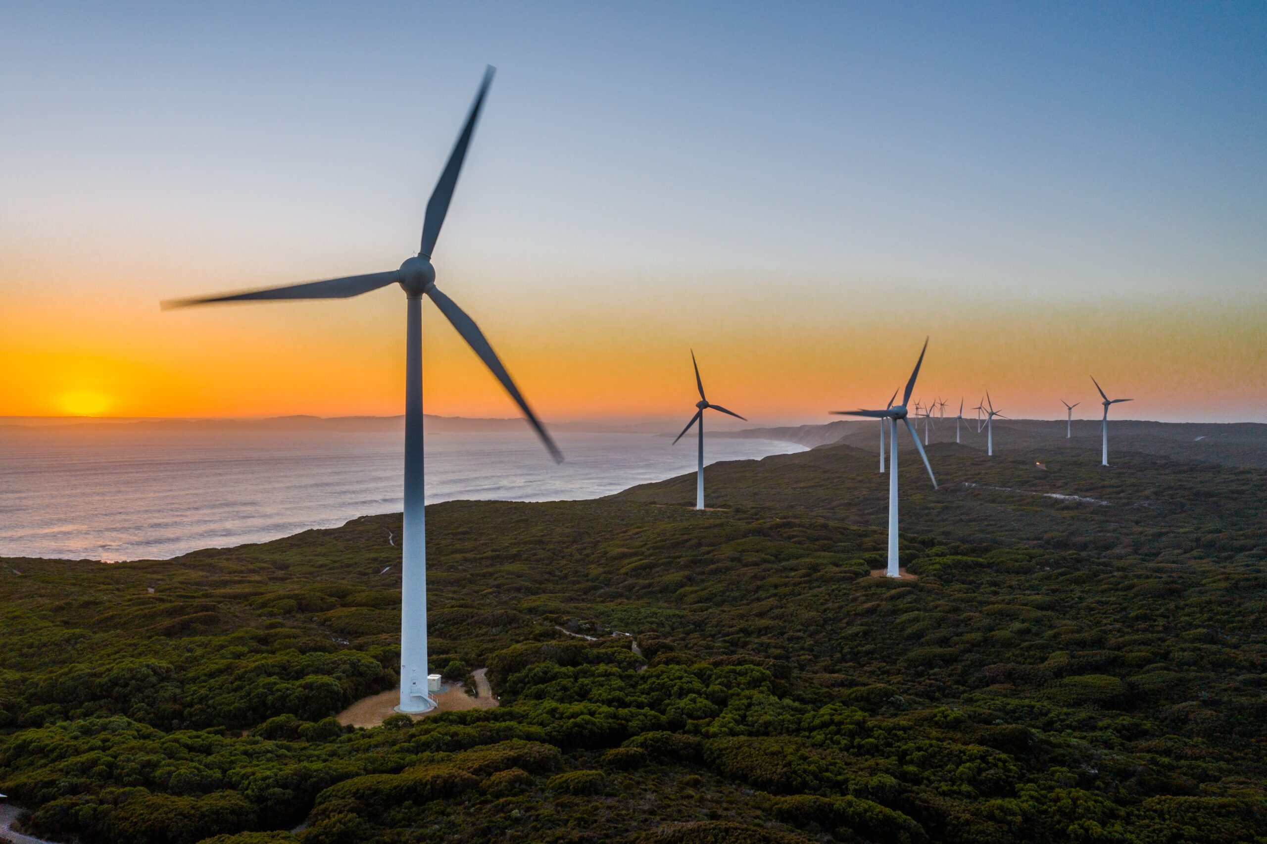 Wind turbines at sunset overlooking a coastal landscape